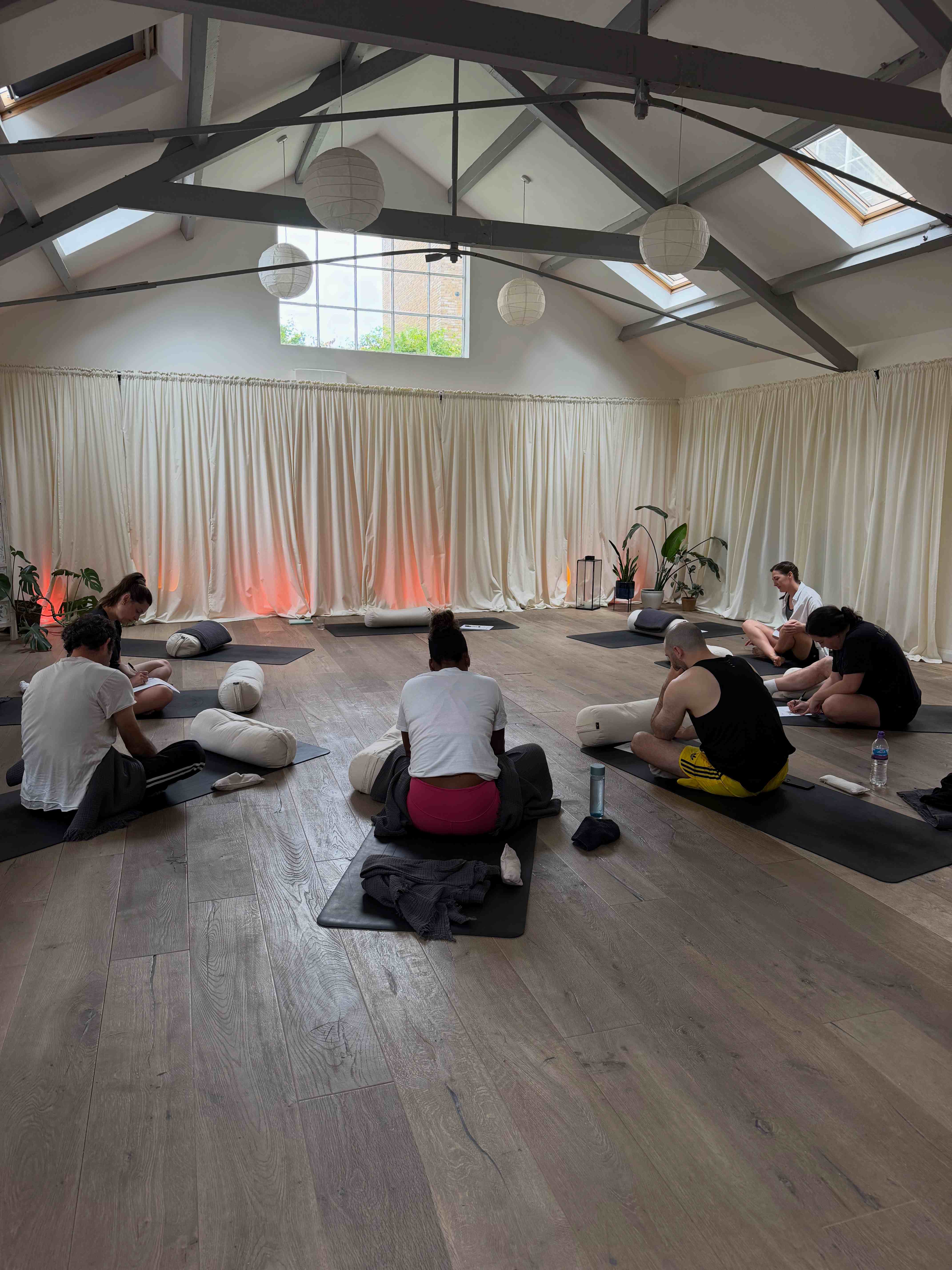People seated on yoga mats in a circle in the Kindroot studio during a workshop session